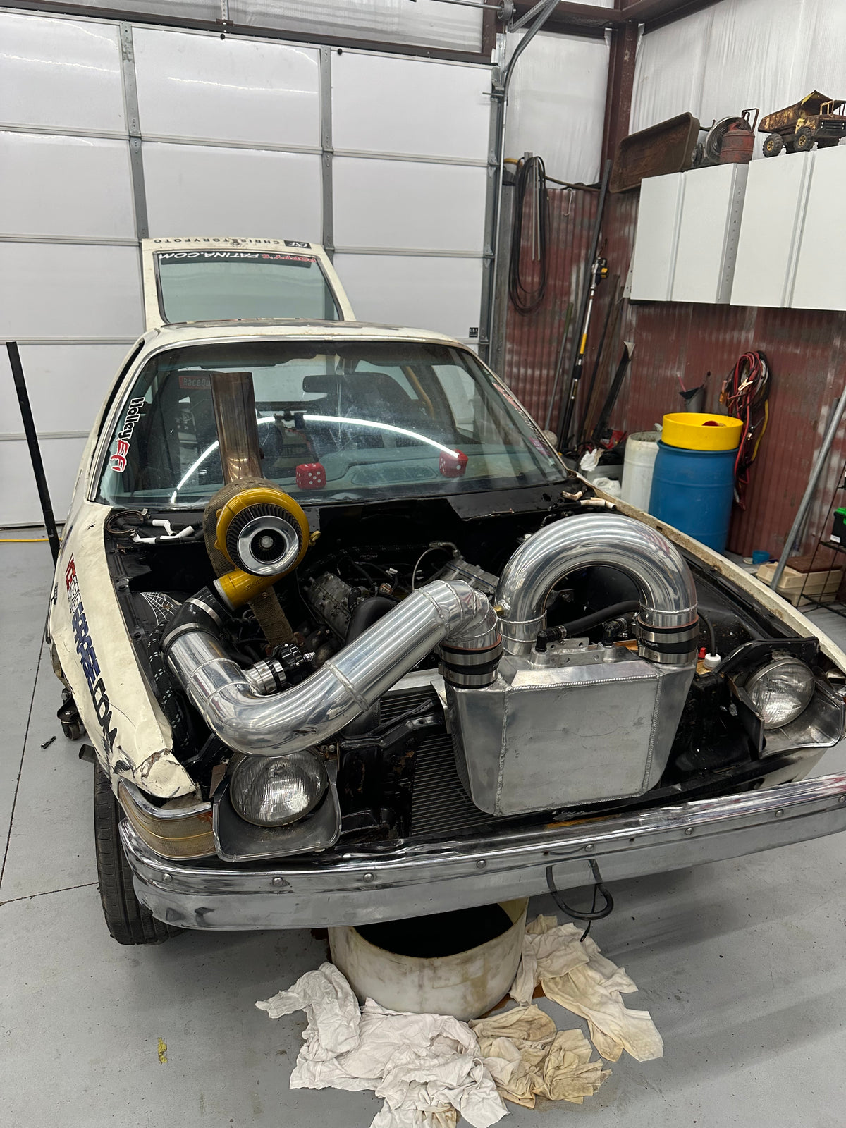 Pit Boss AMC Pacer on stands in the shop with turbo piping fitted