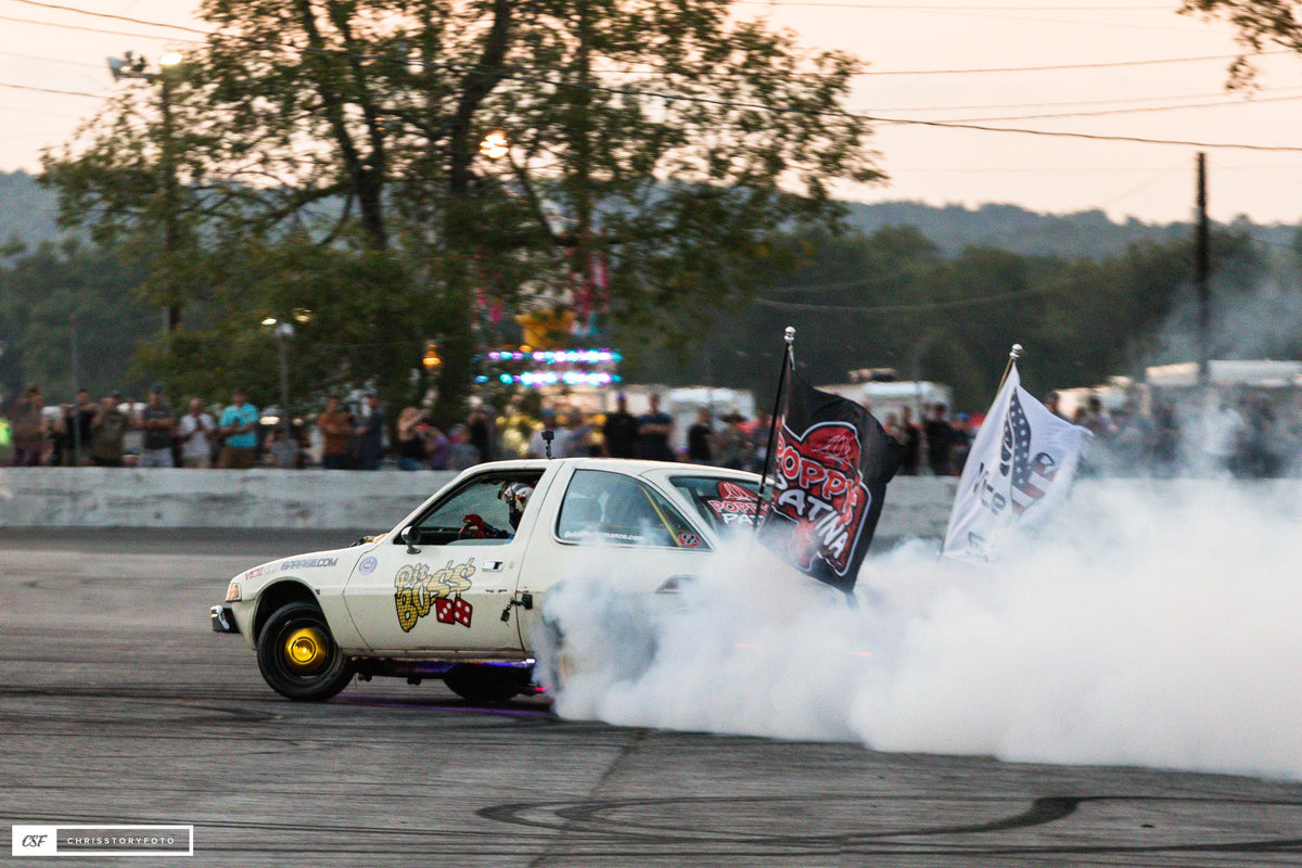 Pit Boss AMC Pacer doing a burnout with trees and a crowd behind
